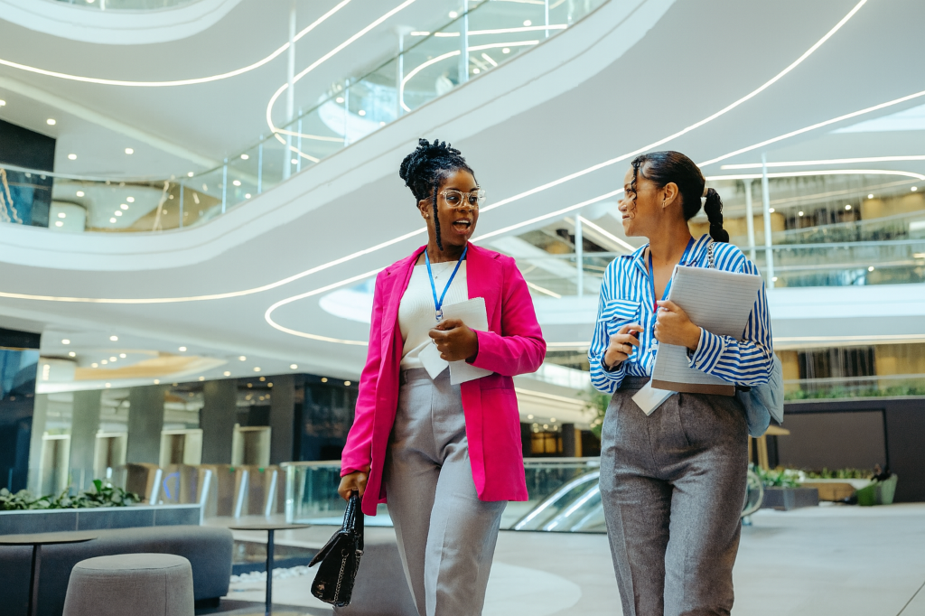 Two professional women walking through a modern, multi-level office