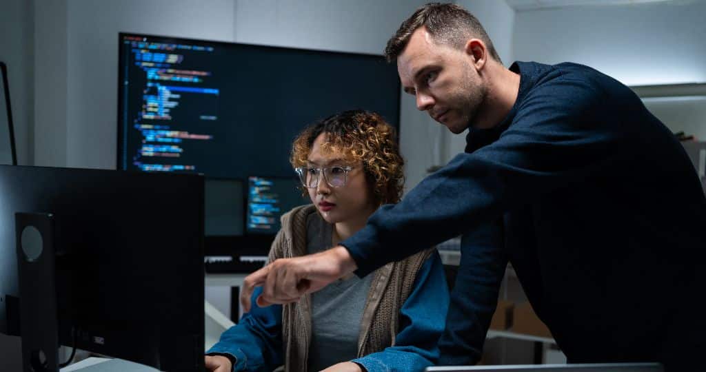 Two engineers reviewing AI-assisted code together on screen - Embedded AI Engineering by JustSolve